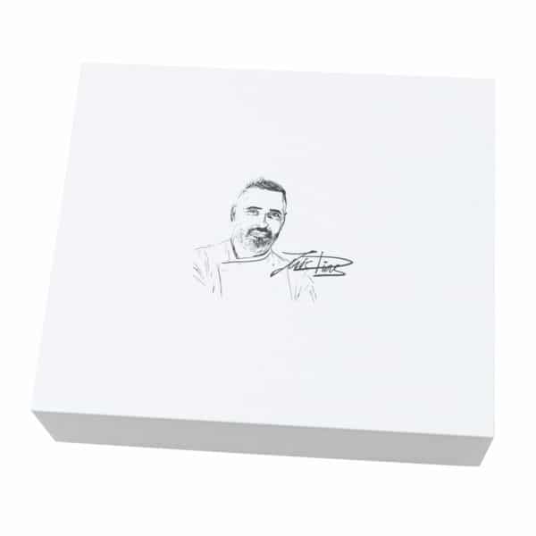 Geschlossene weiße Geschenkbox mit einer Skizze und Unterschrift von Luis Dias auf dem Deckel.